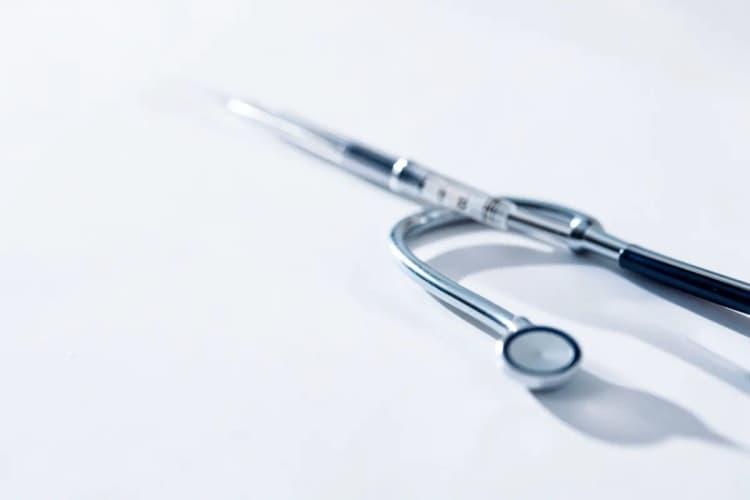 Instrumentos médicos como seringa e estetoscópio, simbolizando tratamento médico.