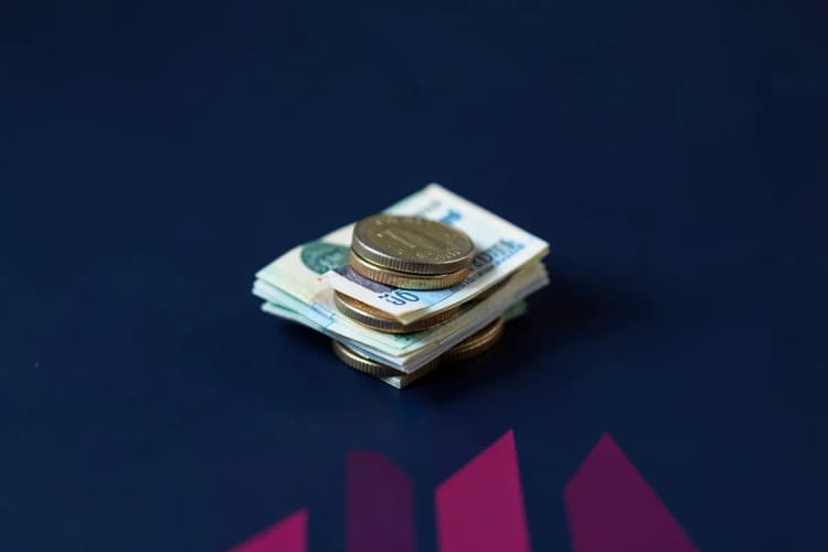 Moedas de euro e notas de dinheiro empilhadas em cima de um gráfico de barras ascendente.