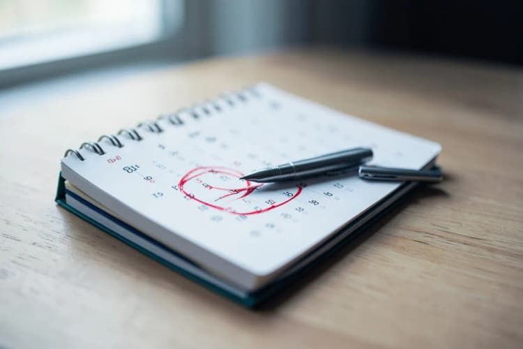 Um calendário aberto com um dia circulado em vermelho e uma caneta ao lado