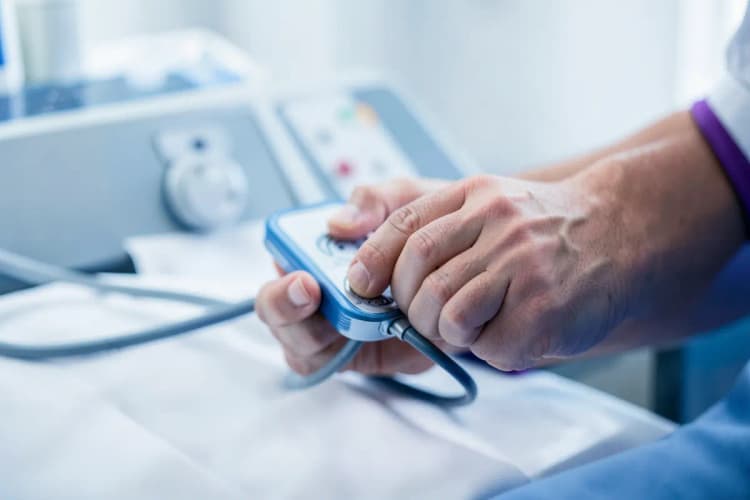 Mãos de um profissional de saúde medindo a pressão arterial de um paciente com esfigmomanômetro.