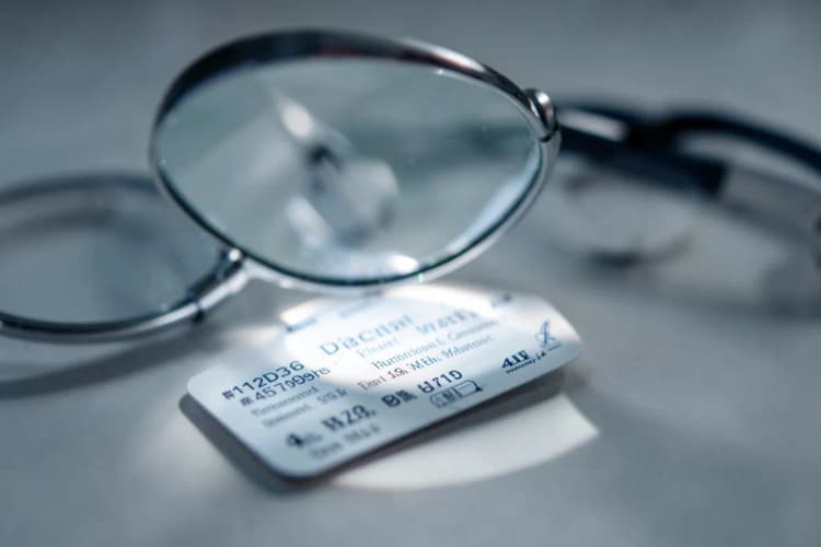 Uma lupa examinando um cartão de identificação profissional de médico com um estetoscópio ao fundo