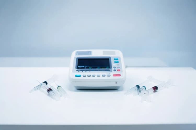 Um conjunto de instrumentos médicos, incluindo um aparelho de ultrassom e seringas, organizados sobre uma mesa em um consultório.