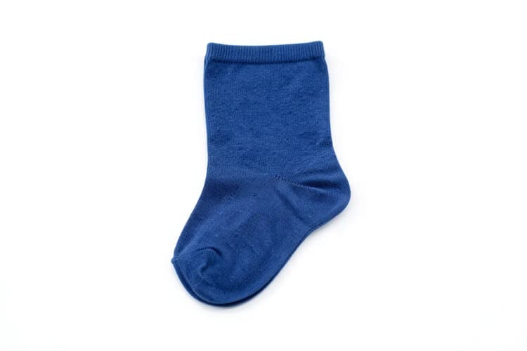 Uma única meia de compressão azul deitada sobre um fundo branco liso.