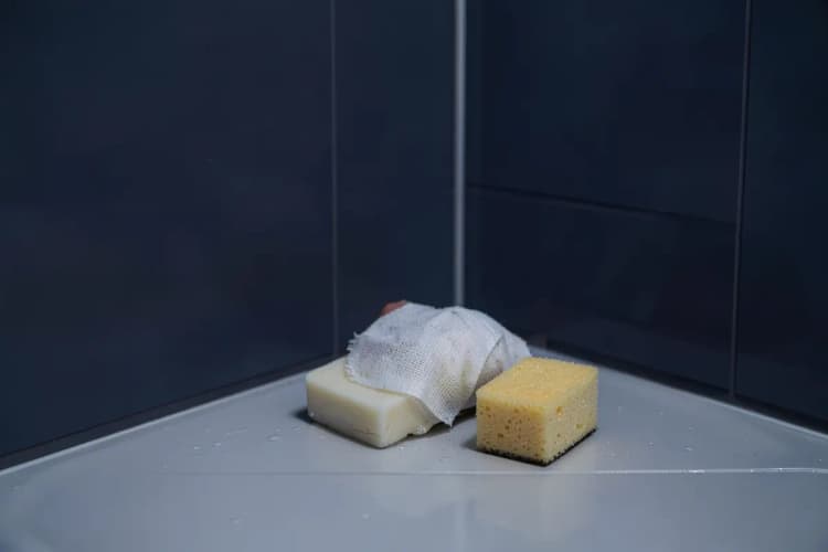 Perna com curativo sendo evitada ao lavar o corpo, com sabonete e esponja longe da área