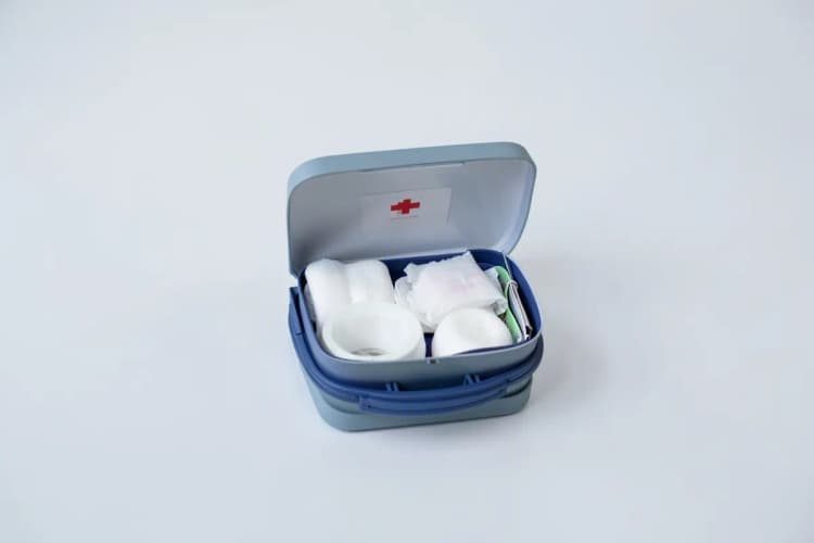 Um kit de primeiros socorros aberto, mostrando bandagens, gaze e fita adesiva, em close-up.
